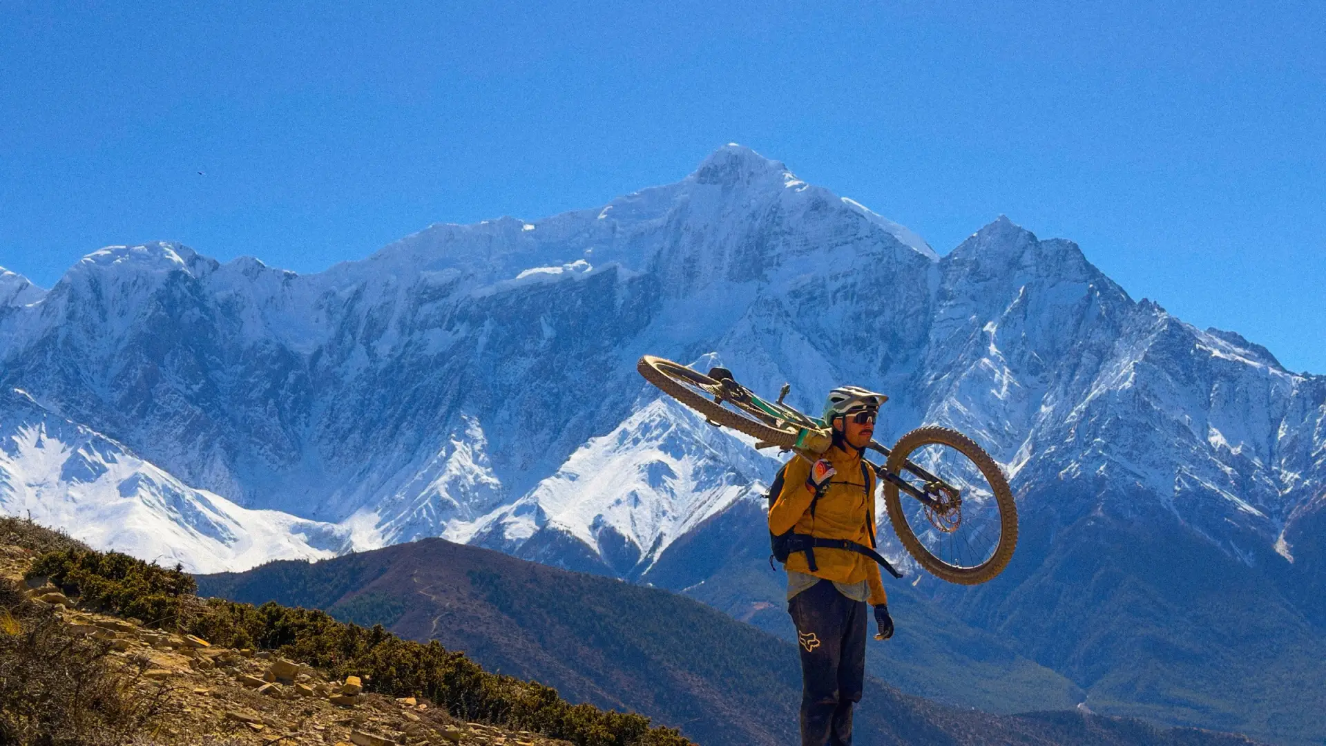 Rider portant son vélo face aux sommets himalayens, Népal